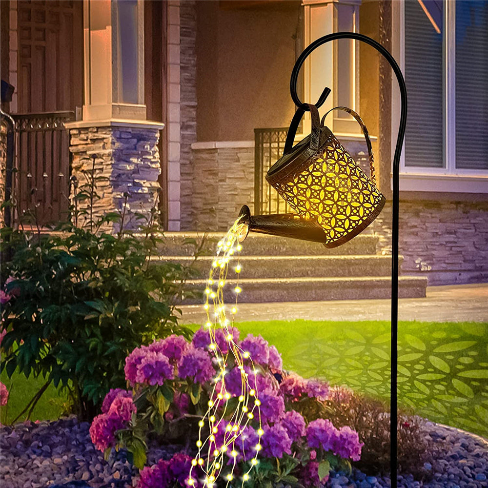 Une lampe de jardin en forme d'arrosoir dans un jardin